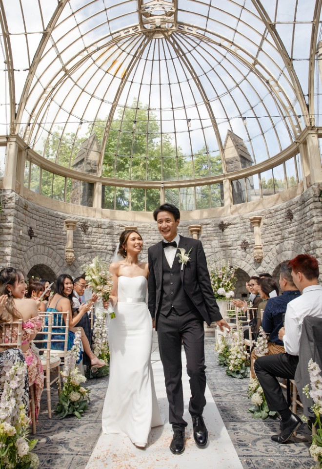 The bride and groom excitedly walking up the aisle after their first kiss in the beautiful orangery at the De Vere Tortworth Court hotel. 