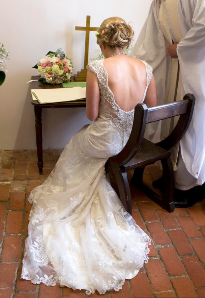Wedding Photographer Bucks, bride in wedding dress sitting down signing the register