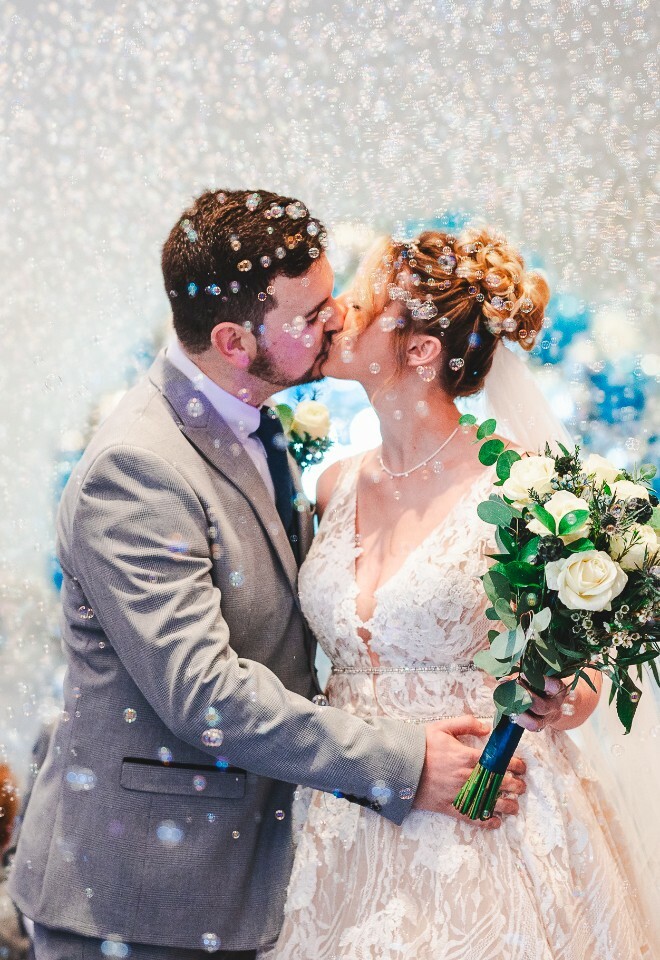 bride and groom kissing amongst bubbles