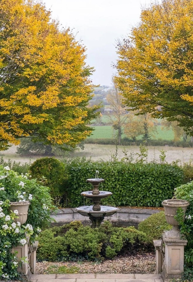 Formal gardens at Henlade House wedding venue in Somerset, featuring a fountain, autumn colour and countryside beyond.