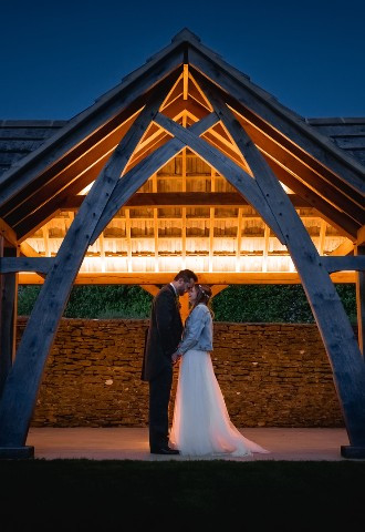 Bride and Groom at night facing each other under pavillion/barn arch