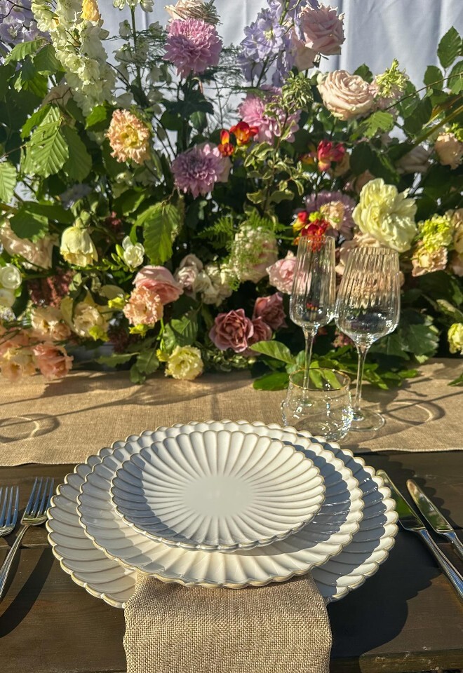 Three stacked waffle rimmed plates with rustic napkin and colourful flower centre piece.