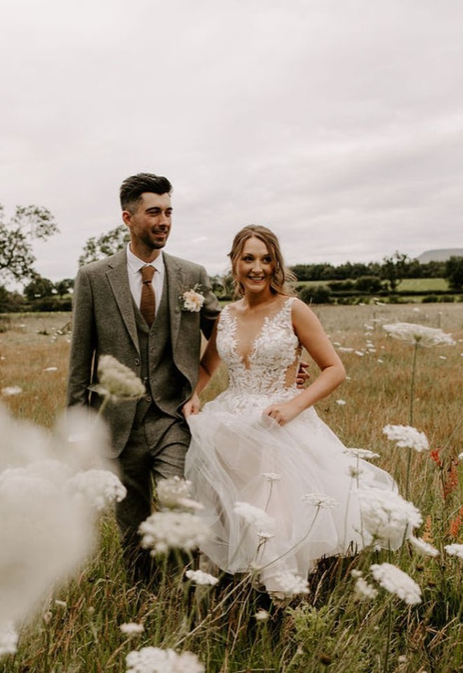 Bride & groom walking through the fields after marrying at Eden wedding barn Cumbria