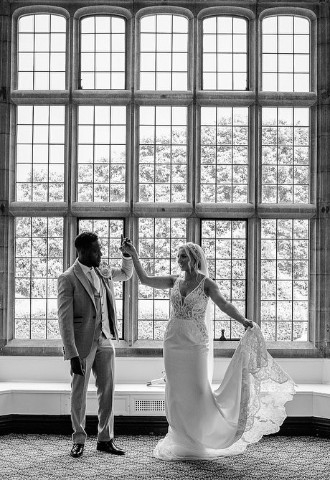 Black and white photo of wedding couple in front of window at Putteridgebury wedding venue
