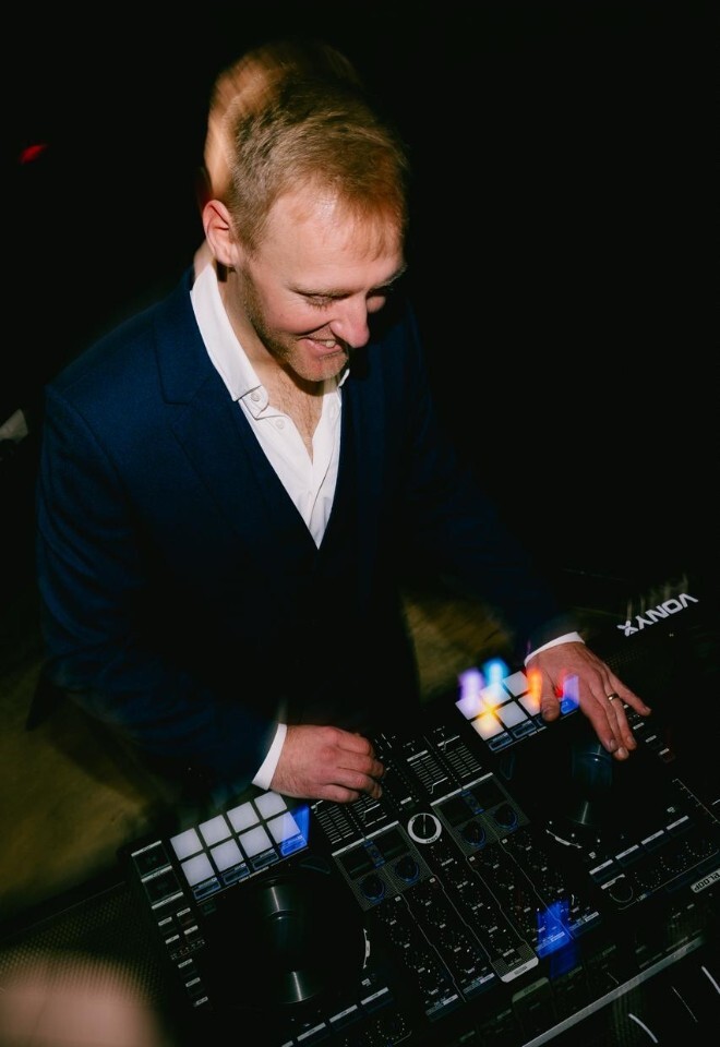 DJ in navy suit performing at a wedding