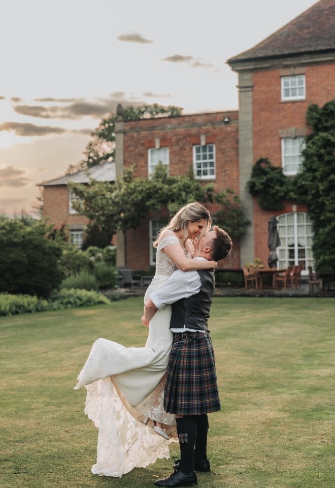 A BRIDE BEING HELD UP BY THE GROOM