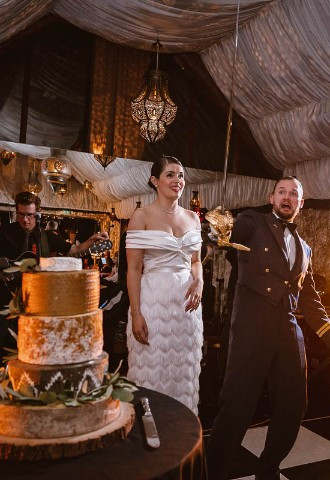 bride and groom preparing to cut the cake with a sword at the crazy bear stadhampton