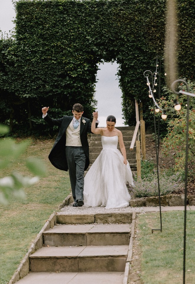 Newlywed couple walking down the steps and celebrating at Heathy Lea Derbyshire wedding venue