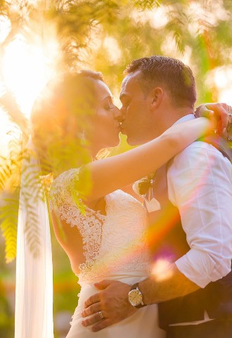 Bride kisses groom in their wedding venue garden