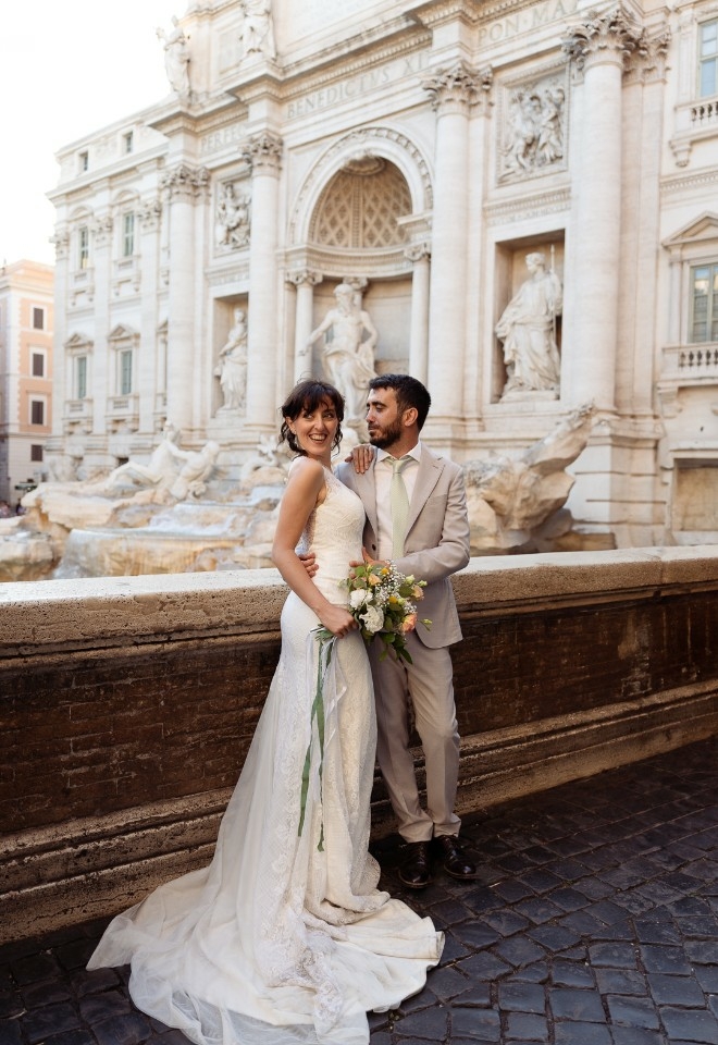 Bride and groom embracing in front of the Trevi Fountain in Rome