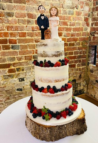 Naked Wedding Cake with fresh fruit and bride and groom Cake Topper with dog made by Celebration Cakes by Catherine Scott in Oxfordshire