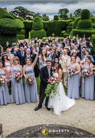 Couple with wedding guests in Topiary Gardens of Billesley Manor
