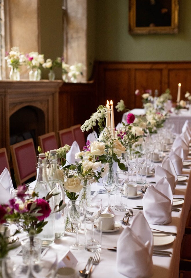 A wedding breakfast tablescape featuring magenta and white flowers in St Edmund Hall Oxford.