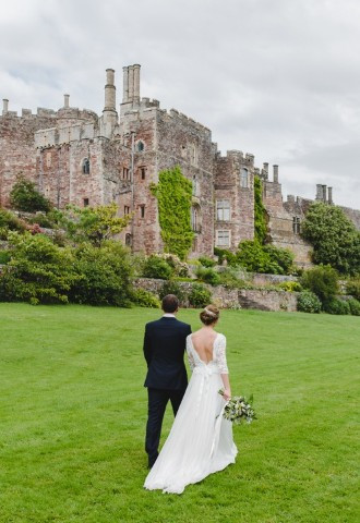 Couple walking around Berkeley Castle grounds on their wedding day