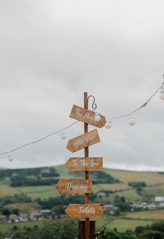 Sign to the wedding with lights strung up at The Stables Wedding Farm