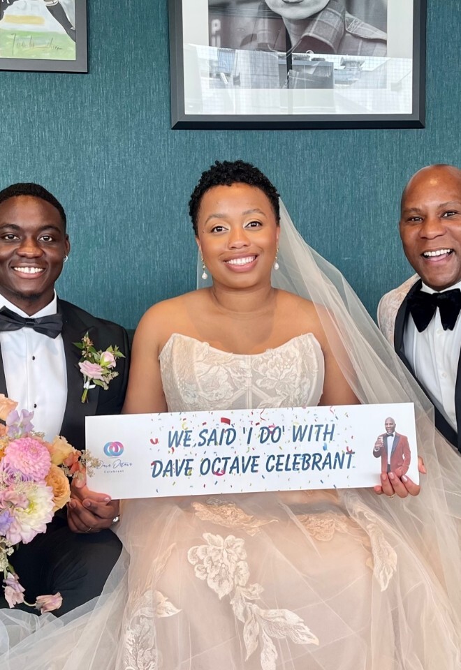 Dave Octave Celebrant with a happy bride and groom smiling and holding my We said I Do with Dave Octave Celebrant sign.