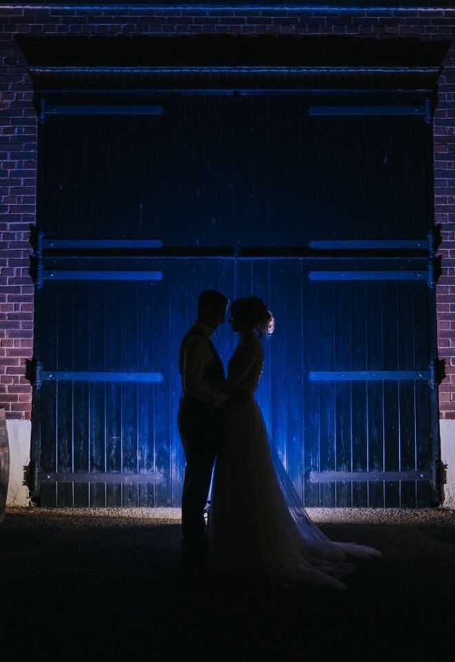 A couple standing in front of one of the barns at a Hertfordshire wedding venue