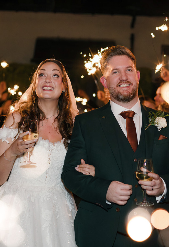 “Bride and groom walking through sparkler exit at Burley Manor Hotel wedding in the New Forest at night”