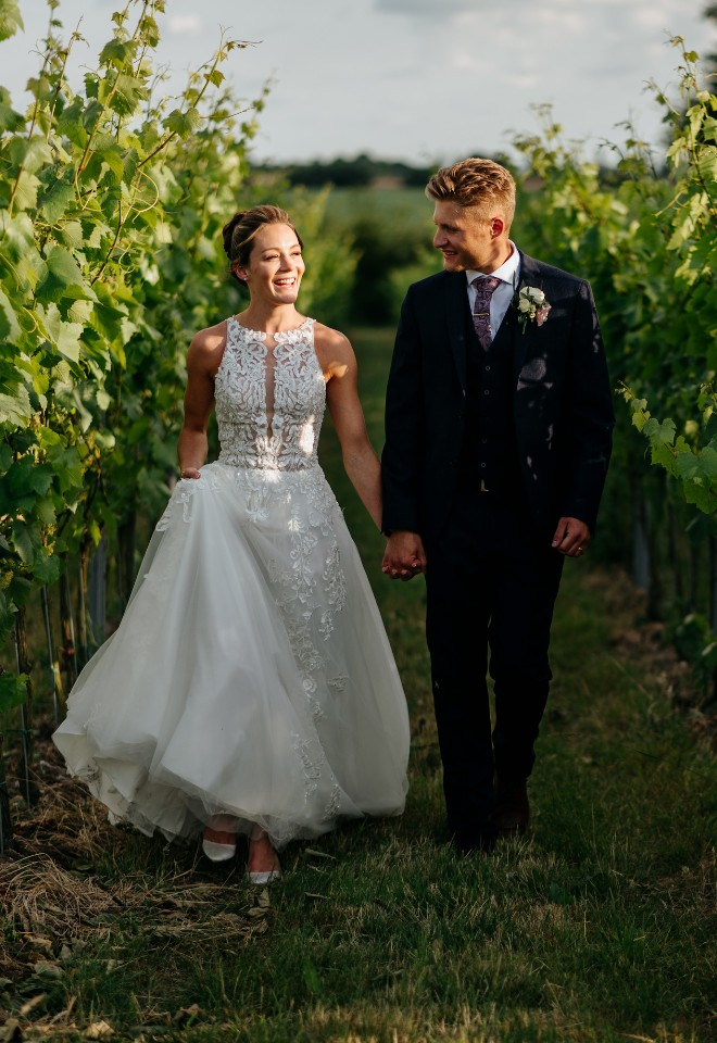 Wedding couple walking through the vineyards at High House wedding venue Essex