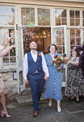 bride and groom leave their wedding ceremony, whilst being showered in confetti by their guests at The Bay Tree Hotel, Burford, Oxfordshire