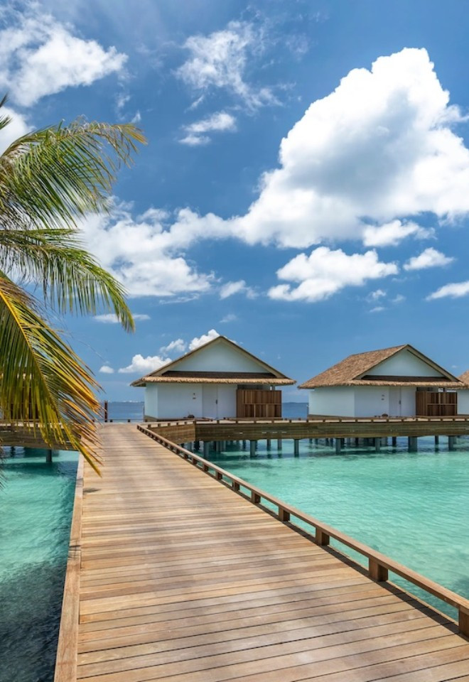 Scenic bridge across a turquoise lagoon to private Maldives villas, creating unforgettable honeymoon experiences with Mantas & Herons.