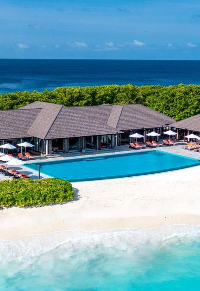 Luxury Maldives beachfront resort with white sandy beaches and turquoise waters, showcasing bespoke honeymoon destinations by Mantas & Herons, independent Maldives travel specialists.