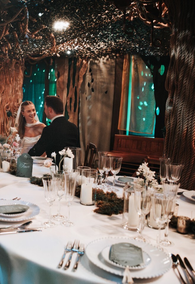 Bride and Groom in Indoor Whispering Woods sat at Nature and Moss styled Wedding Breakfast Tables
