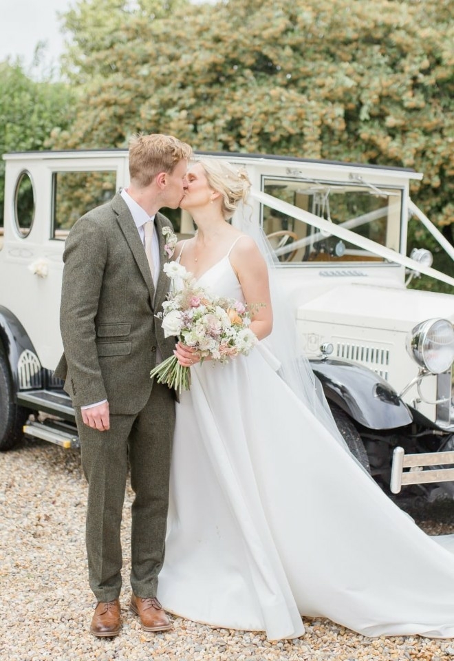 bride & groom kissing by wedding car at hungarian hall suffolk