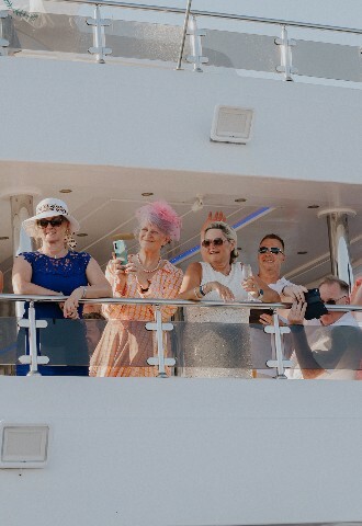 Wedding guests watch bride and groom arrive at the reception on a yacht