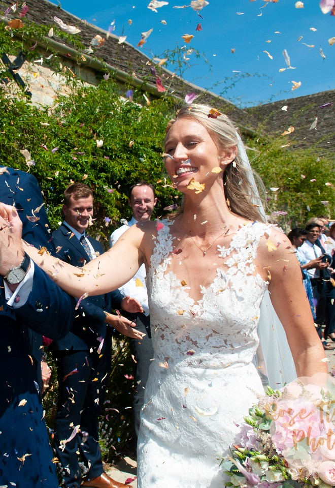 colourful confetti raining down on newlywed bride and groom with blue sky