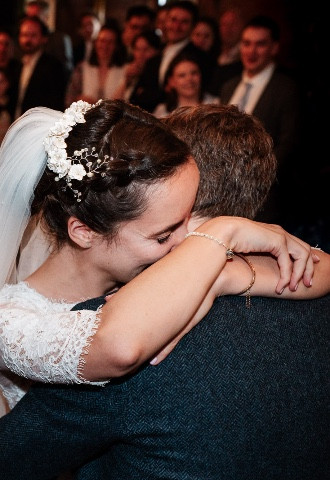 Bride and groom hug during first dance 