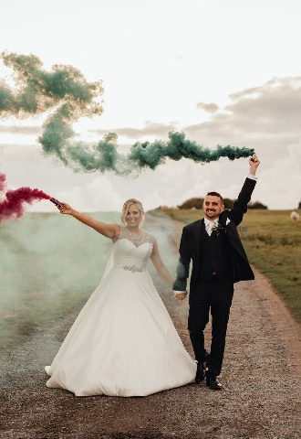 Bride and groom pose with smoke flares at Henblas Country Park, Anglesey