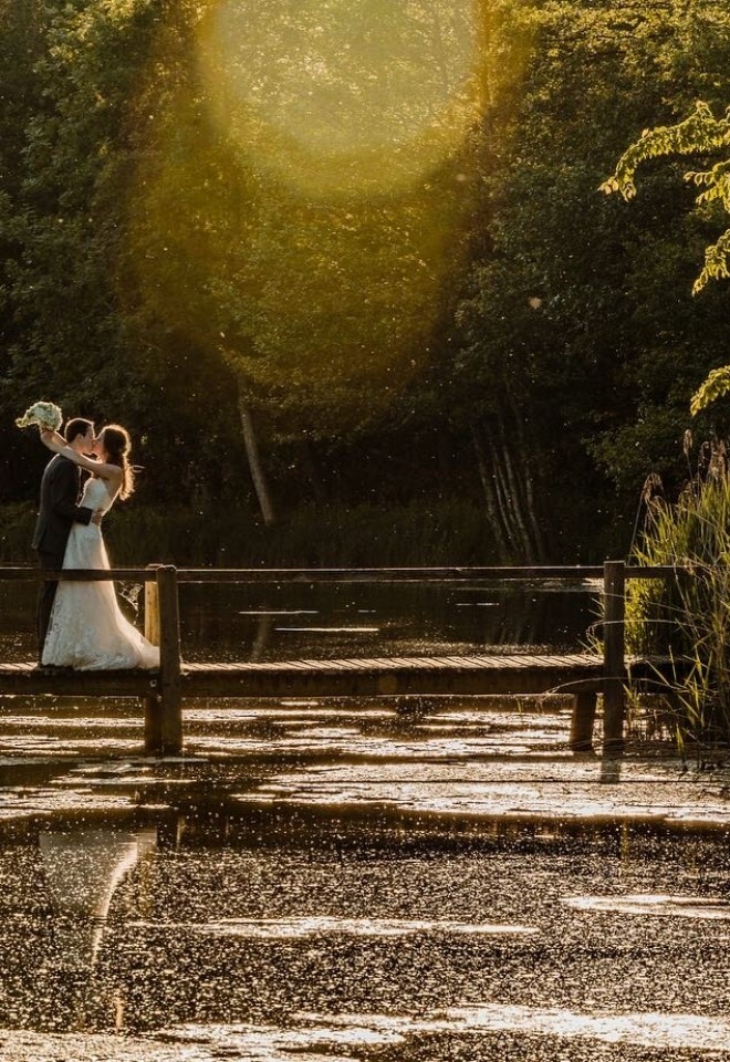 A couple standing on a bridge over a lake at an Oxfordshire wedding venue