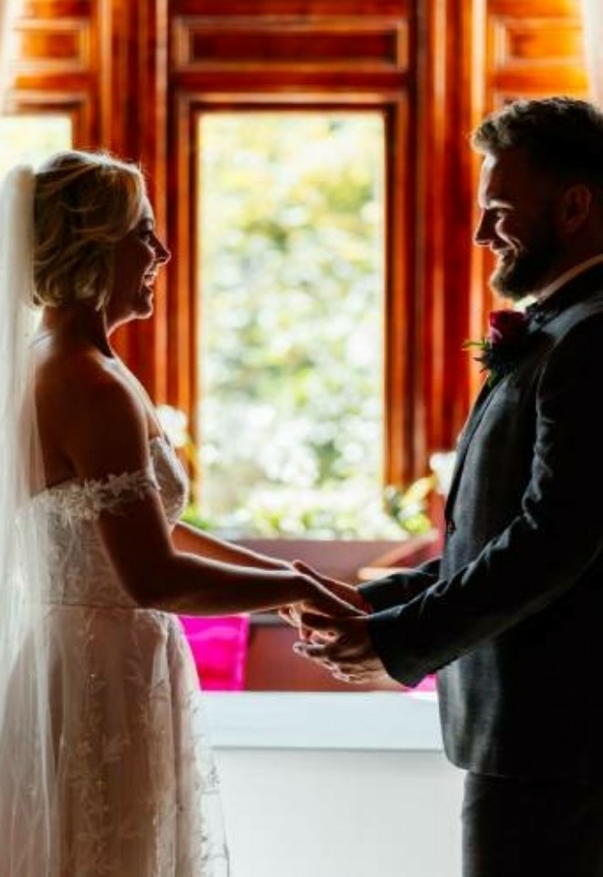 Couple holding hands and laughing in the window of the Somerleyton Suite