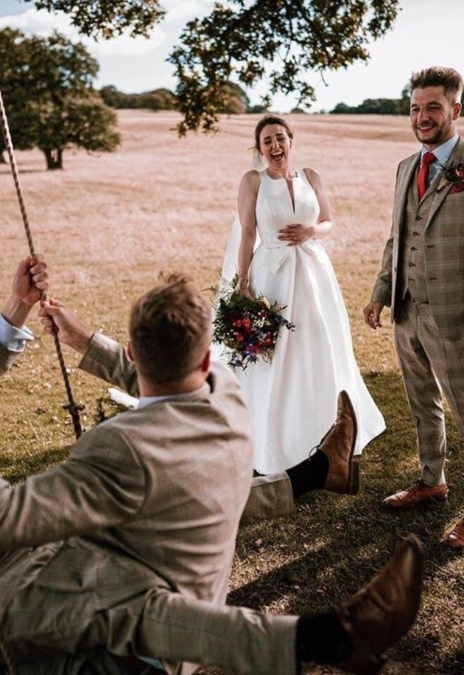 Newly weds laughing at groomsmen on an oak tree swing in the Chatsworth park