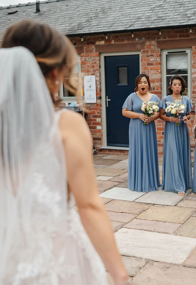 Bride approaching her bridesmaids for their first look in the courtyard at The Cock O’Barton.
