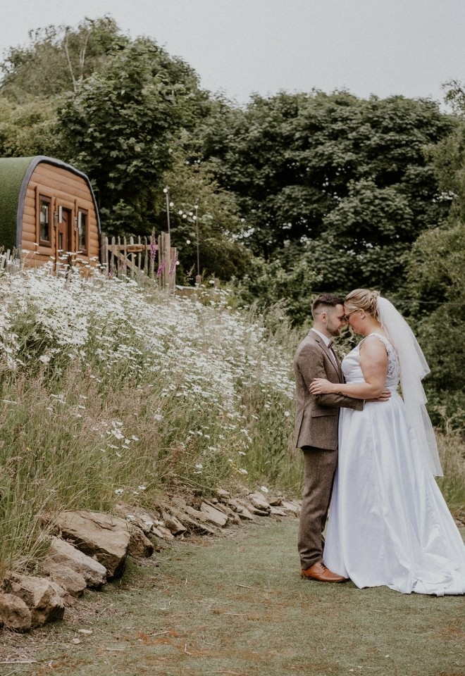 bride & groom by the hobbit houses at The Stables Wedding Farm