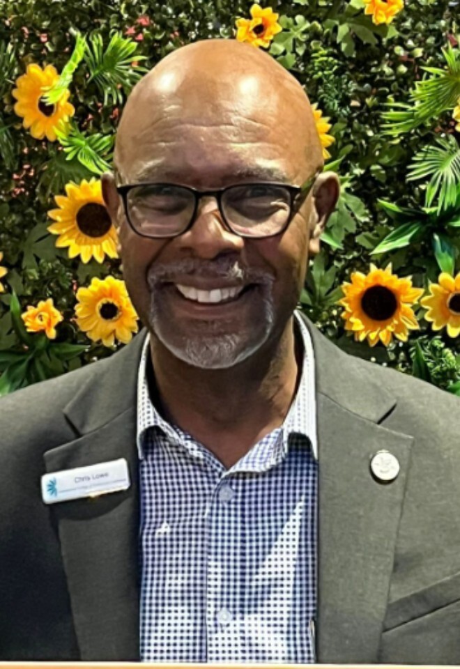 Chris Lowe Wedding Celebrant smiling in front of a floral backdrop in Sittingbourne Kent