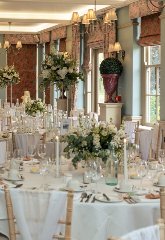Wedding breakfast setup at Washingborough Hall Hotel, with round tables dressed in white linens, floral centrepieces, candles, and elegant soft lighting.