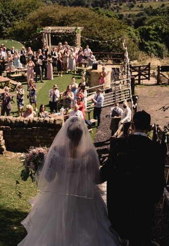 Bride and Groom walking towards ceremony at The Stables Wedding Farm