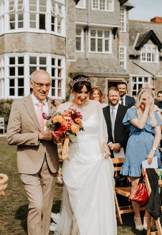 Bride walking down the aisle at her outdoor wedding ceremony at Plas Dinam