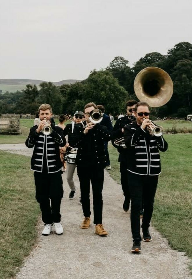 brass band leads wedding guests between venues
