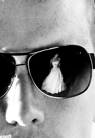 Groom wearing sunglasses with reflection of bride in one of the lenses