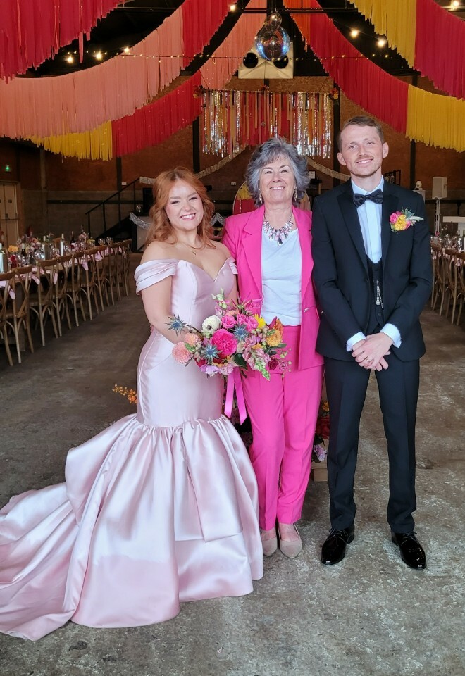 Essex celebrant dressed in a hot pink trouser suit with the bride and groom after the wedding ceremony