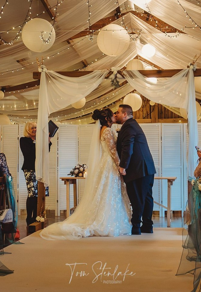 groom kisses bride under canopy