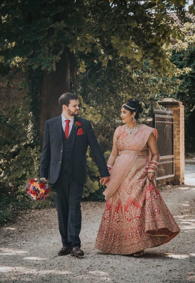 Bride and groom walk hand in hand along a tree-lined path at Washingborough Hall Hotel, dressed in elegant traditional and formal wedding attire.