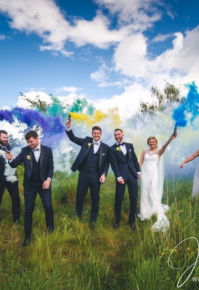 Bride, groom and their wedding party celebrating with colourful smoke bombs in the Cheshire countryside.