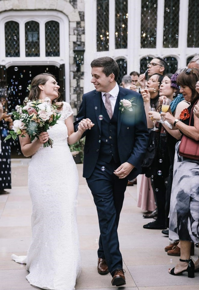 Bride & groom just married, wedding guests blowing bubbles at them outside Hall Place & Gardens in Bexley