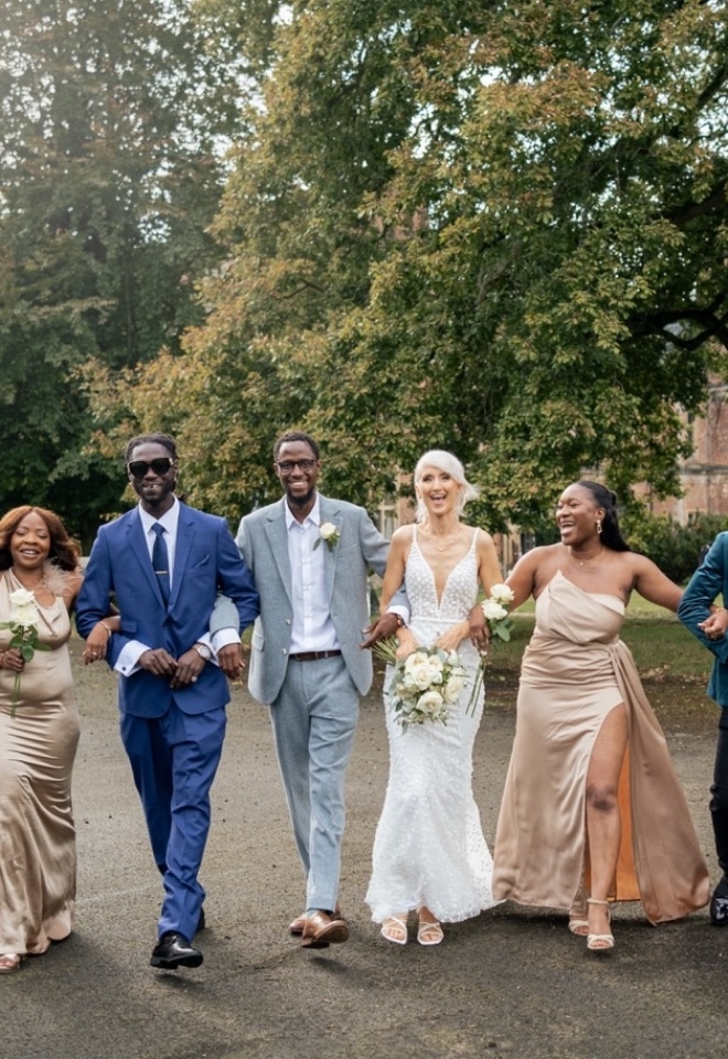 A bridal party walk arm in arm towards the camera at Shaw House 