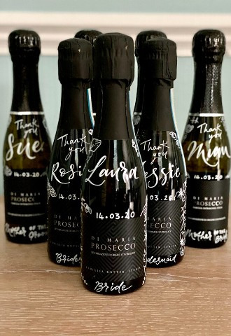 Mini bottles of champagne or prosecco for your wedding party with calligraphy written names for table places and numbers